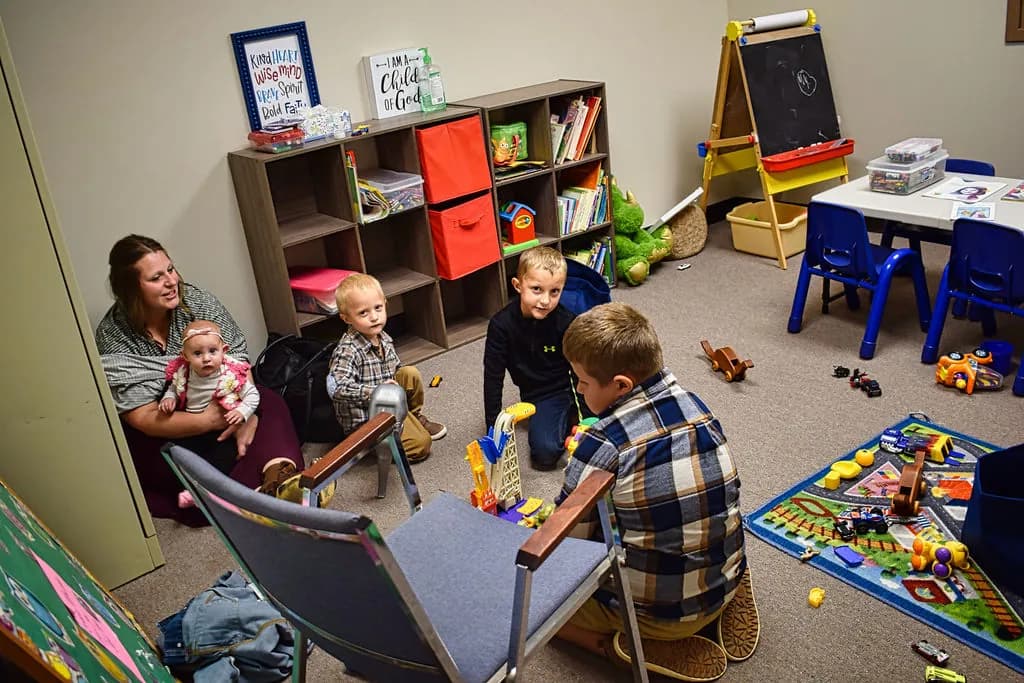 Toddlers playing in the nursery with a mother and her baby