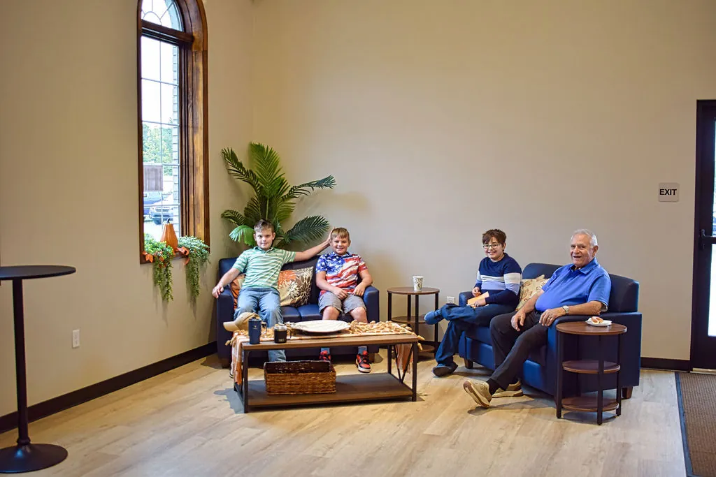 Two boys and two older men visiting on the couches in the fellowship lounge