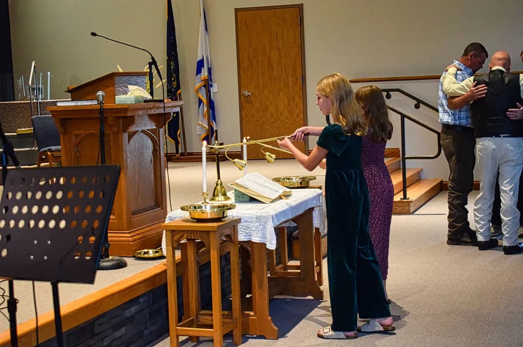 Two girls lighting the candles on the communion table before the service