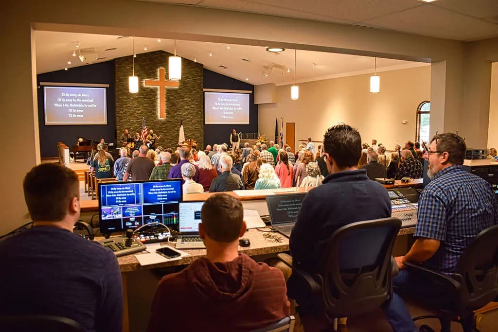 The sound and media team at the booth during worship, the sanctuary full in front of them