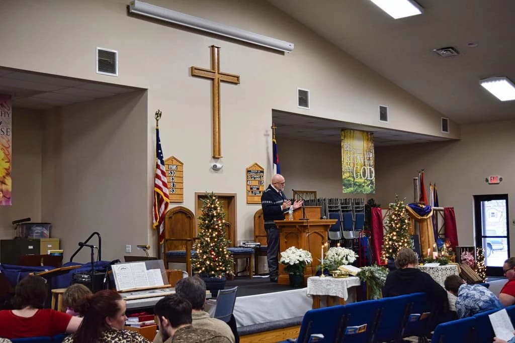 Worship from the back of the room, banners and Christmas trees flanking the platform